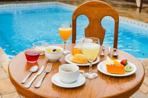 a table with breakfast food and drinks on a table by a pool at Búzios Centro Hotel in Búzios