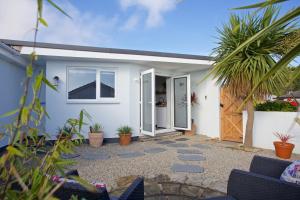 a white house with a door and some plants at Pebbles King Studio in St Ives