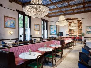 a restaurant with tables and chairs and chandeliers at The Randolph Hotel Oxford, a Graduate by Hilton Hotel in Oxford