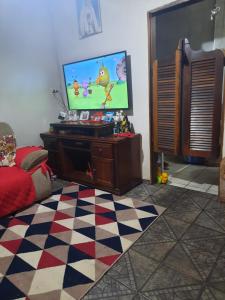 a living room with a tv and a checkered floor at CANTINHO VOLTE SEMPRE in Aparecida