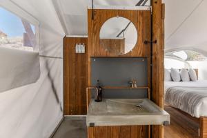 a bathroom with a sink and a clock on the wall at Under Canvas Moab in Moab