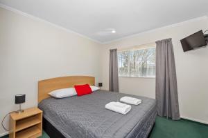 a bedroom with a bed with two towels on it at The Lakes Motel in Twizel