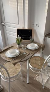 a wooden table with two plates and two chairs at Petit cocon proche gare et commerces in Chantilly