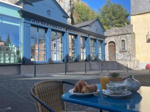 einen Tisch mit einem Teller Brot und einer Tasse Orangensaft in der Unterkunft Logis HOTEL CASTEL DE MIRAMBEL in Lourdes