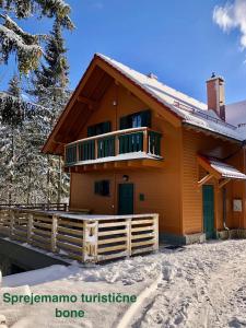 a house with a balcony in the snow at Chalet ANRA Pohorje in Zgornje Hoče