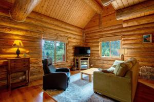 una sala de estar en una cabaña de madera con sofá y silla en The Log Cabin home, en Stevenson