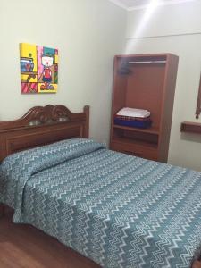 a bedroom with a bed with a blue comforter at Hotel Regência in São Lourenço