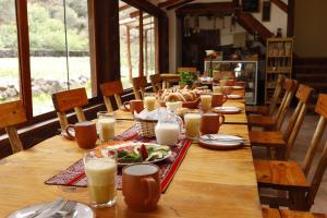 a long wooden table with plates of food and milk at Casita Huaran in Calca