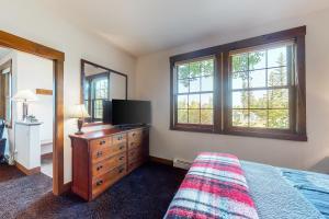 sypialnia z komodą, telewizorem i oknami w obiekcie Bluebird Skies w mieście Granby