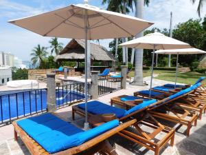 eine Reihe von Liegestühlen und einem Sonnenschirm neben einem Pool in der Unterkunft Casa Lisa in Acapulco