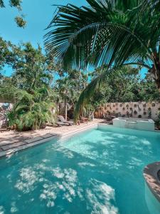 a swimming pool with blue water and palm trees at Trece Lunas Tulum in Tulum