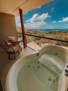 a bath tub in a room with a view of the ocean at Miragem Noronha in Fernando de Noronha