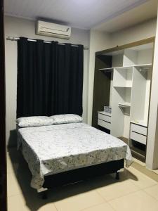 - une chambre avec un lit et un rideau noir dans l'établissement Residencia Canterville, à Olímpia