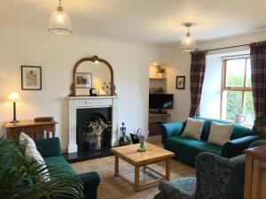 a living room with a blue couch and a fireplace at Glenmuir Cottage in Dornoch