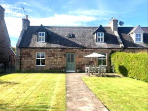 a brick house with a lawn in front of it at Glenmuir Cottage in Dornoch