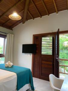 a bedroom with a bed and a tv and a door at Maui Maui Wellness- Taipu de Fora - Barra Grande in Barra Grande