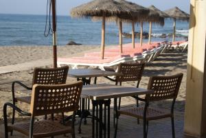 eine Reihe von Tischen und Stühlen am Strand in der Unterkunft Apartamentos La Dorada in La Cala de Mijas