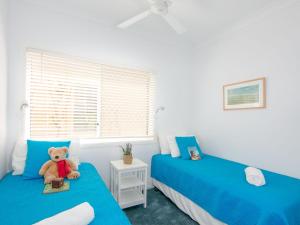 a teddy bear sitting on two beds in a bedroom at Avalon 2 in Yamba