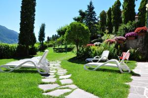 three chairs sitting on the grass in a garden at Charme Hotel Nevada in Molveno