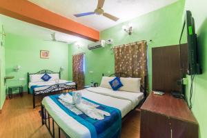 a room with two beds and a television in it at Kiara Hotel Goa in Anjuna