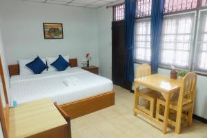 a bedroom with a bed and a table and a desk at The Best House&Hostel in Ban Don Muang