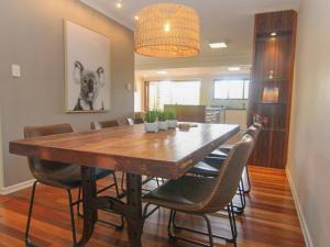 a dining room with a large wooden table and chairs at Two Sands by Discover Stradbroke in Point Lookout