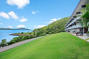 a building with a grassy lawn next to a body of water at Lagoon Beachfront Lodge 206 on Hamilton Island by HamoRent in Hamilton Island