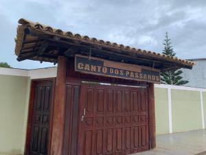 een grote houten garagedeur met een bord erop bij Canto Dos Pássaros in Caraíva