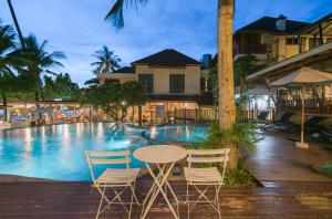 een tafel en stoelen naast een zwembad bij Mac Resort Hotel in Ko Chang