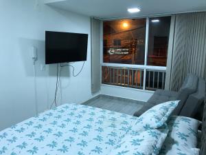 um quarto com uma cama, uma televisão e uma janela em Aparta estudio amoblado Medellin, San joaquin em Medellín