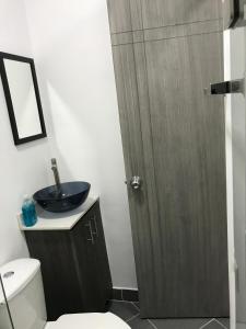 La salle de bains est pourvue de toilettes et d'un lavabo avec une porte en bois. dans l'établissement Aparta estudio amoblado Medellin, San joaquin, à Medellín
