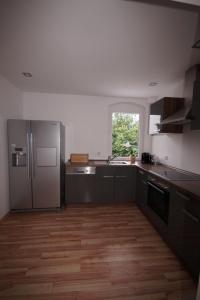 a kitchen with stainless steel appliances and wooden floors at MR-Ferienwohnung - Wohnung Hönnersum in Harsum