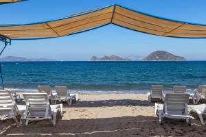 eine Gruppe von Stühlen und Sonnenschirmen am Strand in der Unterkunft Yelken Mandalinci Spa&Wellness Hotel in Turgutreis