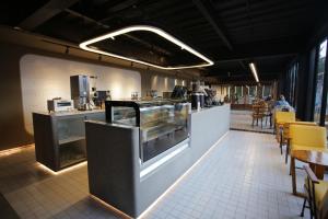 a restaurant with a counter and tables and chairs at Creative Restart Hotel - CARTEL Bandung in Bandung