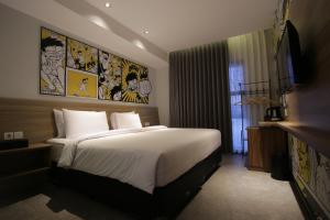 a bedroom with a large bed and a television at Creative Restart Hotel - CARTEL Bandung in Bandung