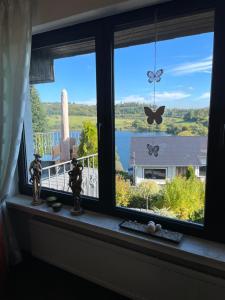 ein Fenster mit Blick auf einen See und Schmetterlinge in der Unterkunft Traumhaus am Maar in Schalkenmehren