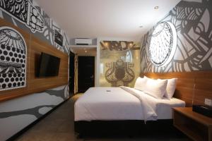 a bedroom with a white bed and a tv at Creative Restart Hotel - CARTEL Bandung in Bandung