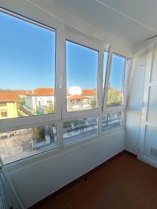 Habitación con 4 ventanas y vistas a un edificio. en Bonito duplex cerca de la playa y de Santander, en Santa Cruz de Bezana