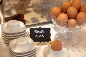 una mesa con un plato de huevos y platos en Hôtel du Port en Nogent-sur-Marne