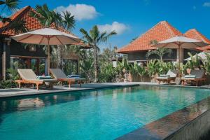una piscina in un resort con sedie e ombrelloni di SUNSHINE VILLAS UBUD ad Ubud
