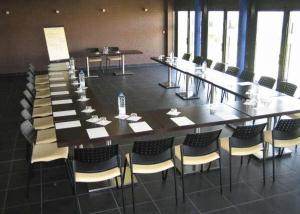 une grande salle de conférence avec une grande table et des chaises dans l'établissement Résidence Hôtelière des Ondes, à Saint-Lys