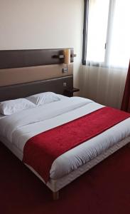 a bedroom with a large bed with a red blanket at Résidence Hôtelière des Ondes in Saint-Lys