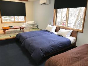 a bedroom with a large bed with a blue blanket at ALP Lodge in Hakuba