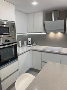 a kitchen with white cabinets and stainless steel appliances at ocean experience / EXPERIENCE HOLIDAYS TENERIFE in Callao Salvaje