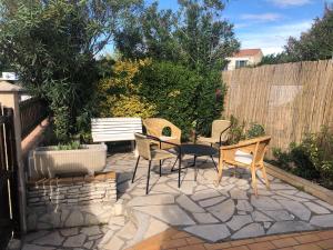 un patio avec des chaises et un banc dans une arrière-cour dans l'établissement Confort et calme à deux pas des plages de Valras, à Valras-Plage