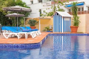 een zwembad met blauwe en witte stoelen en een parasol bij Hotel Dwo Les Palmeres in Calella