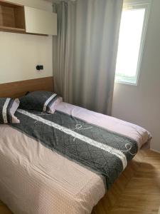 1 cama en un dormitorio con ventana en Mobil home BASSET au camping à St Hilaire de Riez 400m de la mer en Saint-Hilaire-de-Riez