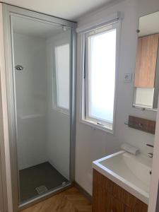 a bathroom with a glass shower and a sink at Mobil home BASSET au camping à St Hilaire de Riez 400m de la mer in Saint-Hilaire-de-Riez