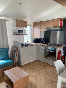 a kitchen with a couch and a table in a room at Mobil home BASSET au camping à St Hilaire de Riez 400m de la mer in Saint-Hilaire-de-Riez