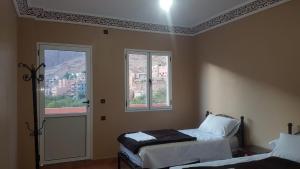 a bedroom with two beds and two windows at Auberge Restaurant Fatihi Freres in Tinerhir